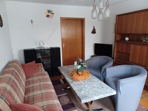 Een woonkamer met een bank, een salontafel, een televisie en een kast.