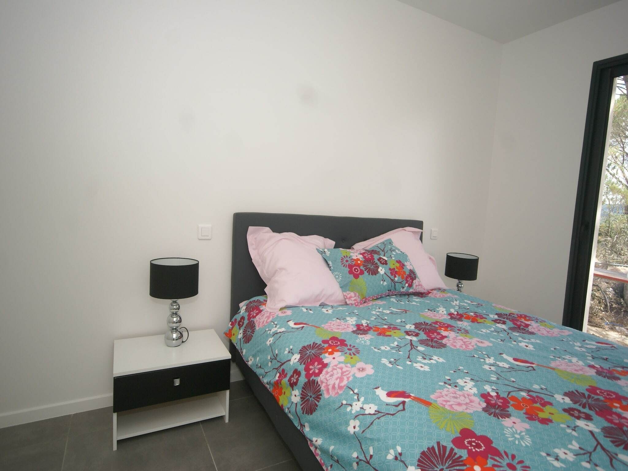 Une chambre à coucher avec un lit, deux tables de chevet et une fenêtre.