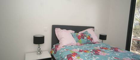 Une chambre à coucher avec un lit, deux tables de chevet et une fenêtre.