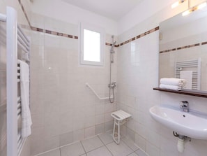 A modern bathroom with a walk-in shower, a white sink, and a towel rack.