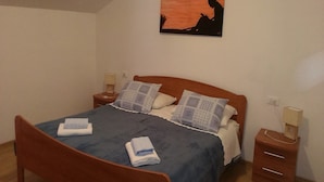 Een slaapkamer met een houten bed, twee nachtkastjes, een wandlamp en een schilderij aan de muur.