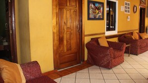 Un vestíbulo de hotel con puerta de madera, sofás estampados y suelo de baldosas.