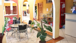 Un café con terraza, un refrigerador de Coca-Cola y plantas en macetas.