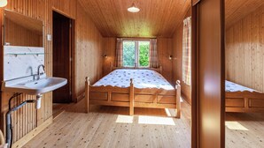 Une chambre dans une cabane en bois, avec un lit, un lavabo et une fenêtre.