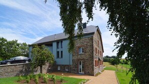 A two-story stone building with a blue exterior and a gravel driveway leading to a wooden gate. - Holiday home in Cetturu with sauna (Cetturu)