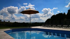 A swimming pool with a wooden deck, lounge chairs, and an umbrella. - Holiday home in Cetturu with sauna (Cetturu)