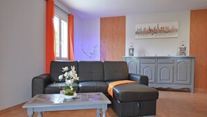 Una sala de estar con un sofá de cuero negro, una mesa de centro y un aparador.