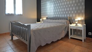 Un dormitorio con cama, dos mesitas de noche, un radiador y una ventana con cortinas.