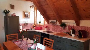 A cozy kitchen with wooden beams, a dining table with chairs, and a small island with a sink.
