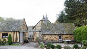 A traditional stone building with a steeply pitched roof, a small porch, and a gravel driveway leading to a wooden door.