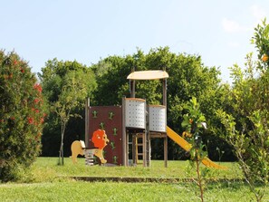 Ein Spielplatz mit Rutsche, Kletterwand und Schaukeln.