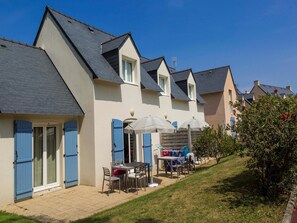 Eine Reihe Häuser mit einer Terrassenfläche, die Gartenmöbel und Sonnenschirme bietet.