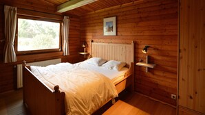 Un dormitorio de cabaña de madera con una cama, una ventana y un cuadro en la pared.