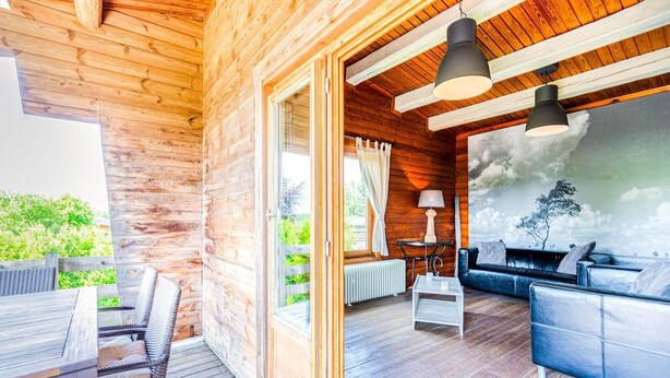 Una cabaña de madera con un espacio de patio amoblado con un sofá, una mesa y sillas.