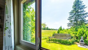 Una ventana con vista a un jardín, un banco de madera y una estructura de piedra.