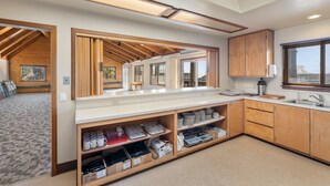 A modern kitchen with wooden cabinetry, a countertop with kitchenware, and a view of the outdoors through a window. - Harbor Lite Lodge (Fort Bragg)
