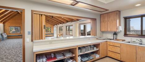 A modern kitchen with wooden cabinetry, a countertop with kitchenware, and a view of the outdoors through a window.