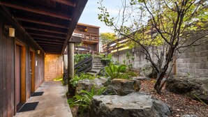 A narrow concrete pathway flanked by wooden doors and a stone wall. - Harbor Lite Lodge (Fort Bragg)