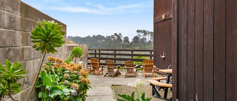 Un espace patio avec un chemin en béton, des chaises et des tables en bois.