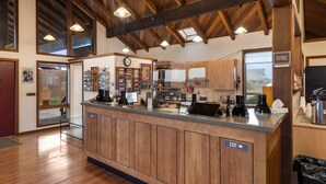 A spacious hotel lobby with a wooden reception desk, a clock, and a view of the outdoors. - Harbor Lite Lodge (Fort Bragg)