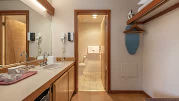 Un baño moderno con tocador de madera, un espejo grande y un perchero para toallas.
