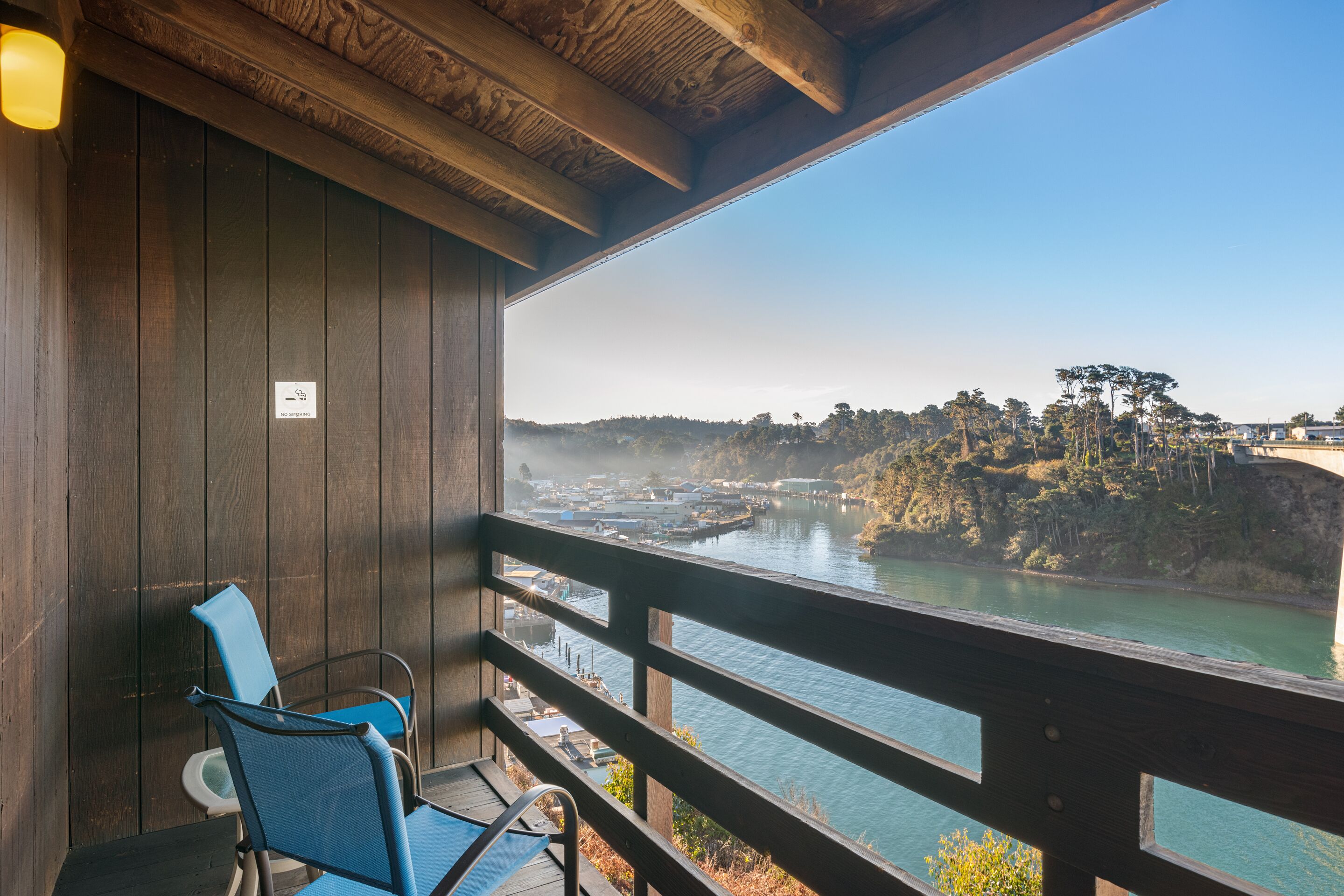 A wooden balcony with a view of a river and distant hills.