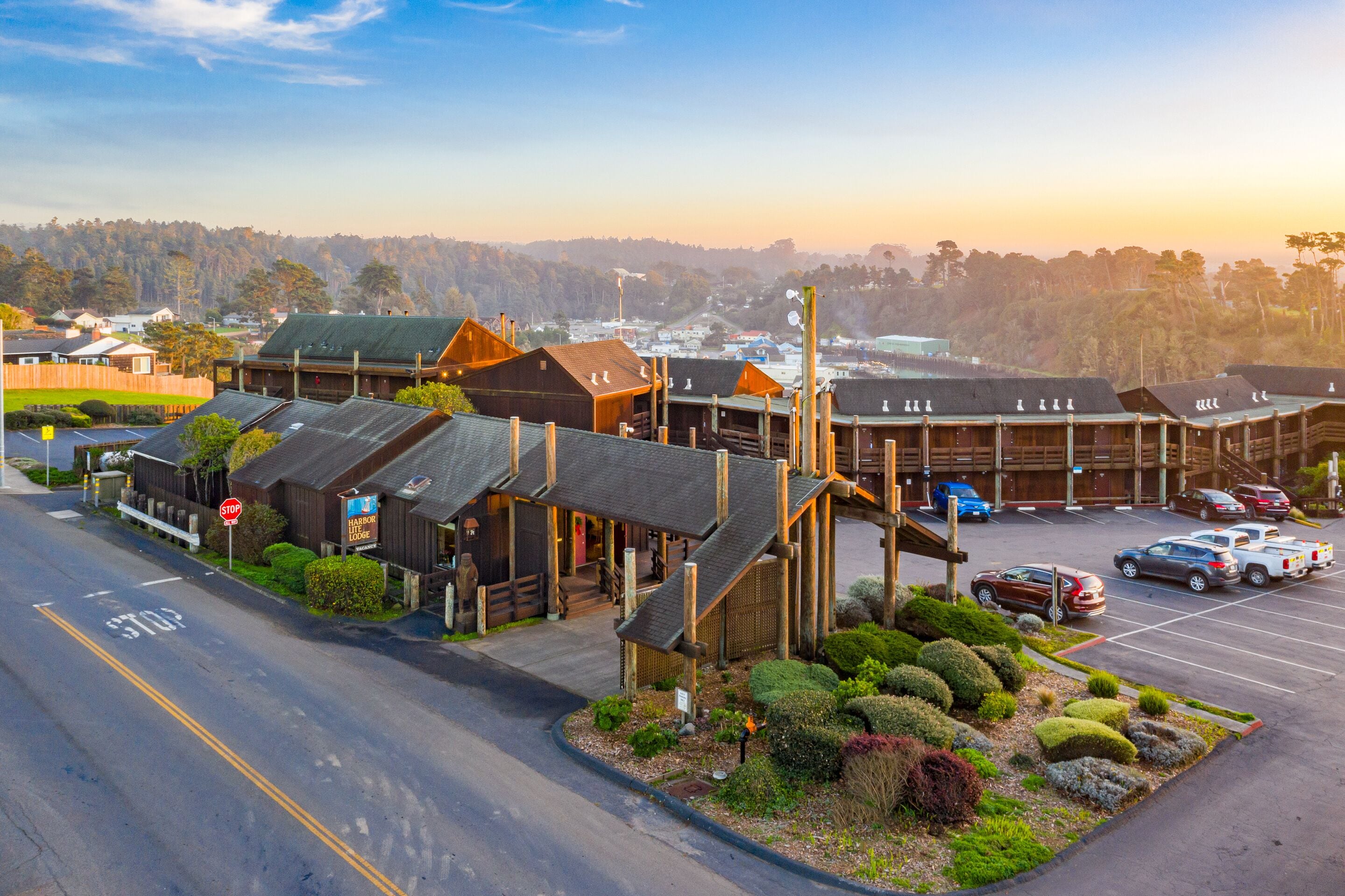 A row of wooden cabins with a parking lot in front.