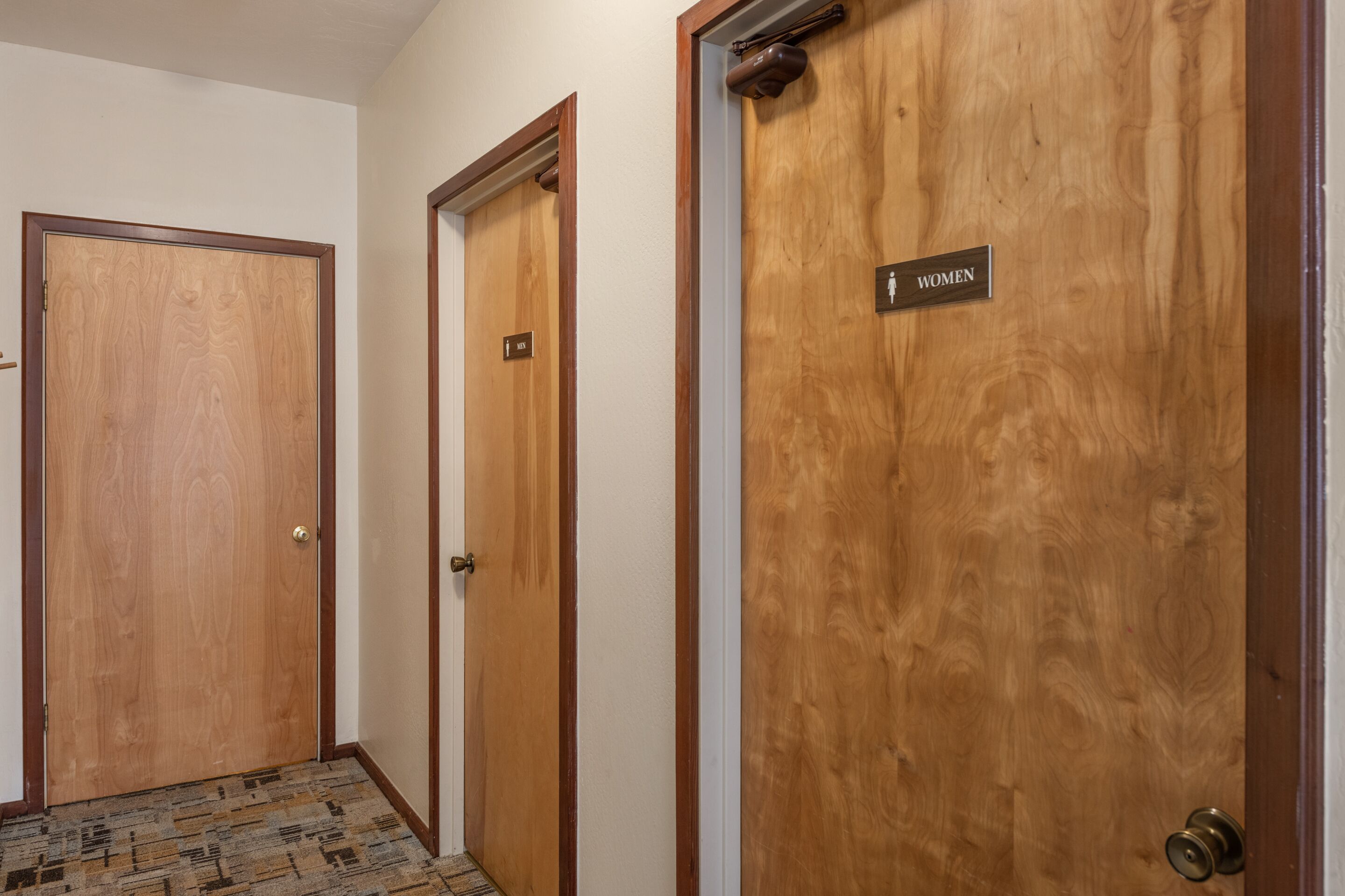 Tres puertas de madera con una placa que indica un baño de mujeres.