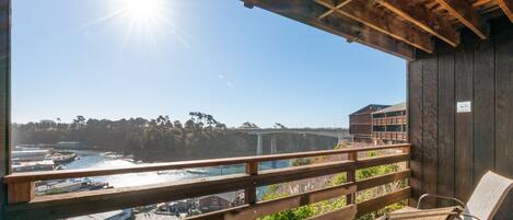 A wooden deck with a view of a coastal area, including a bridge and buildings.