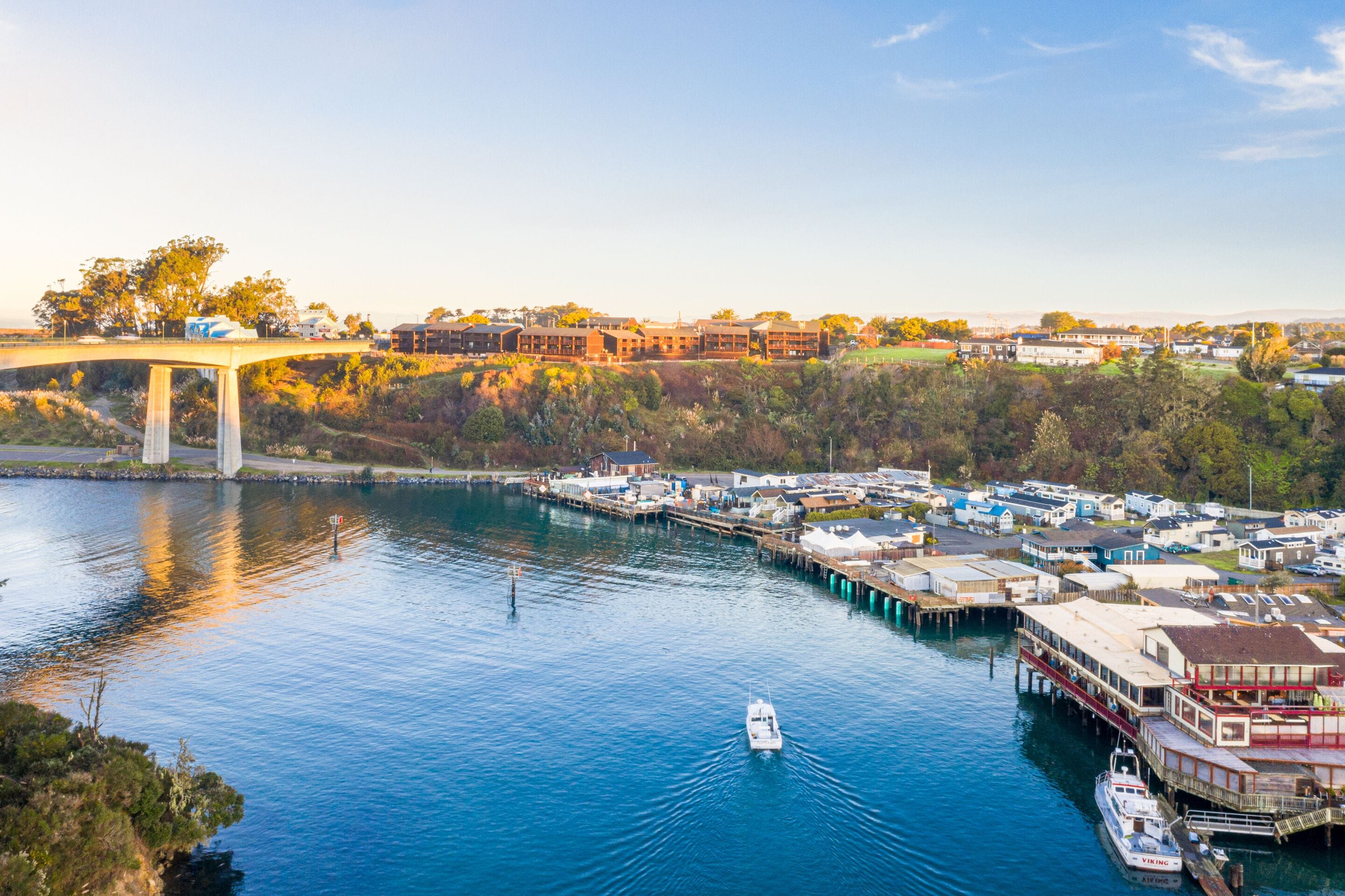 A waterfront area with a bridge, docked boats, and buildings along the shore.