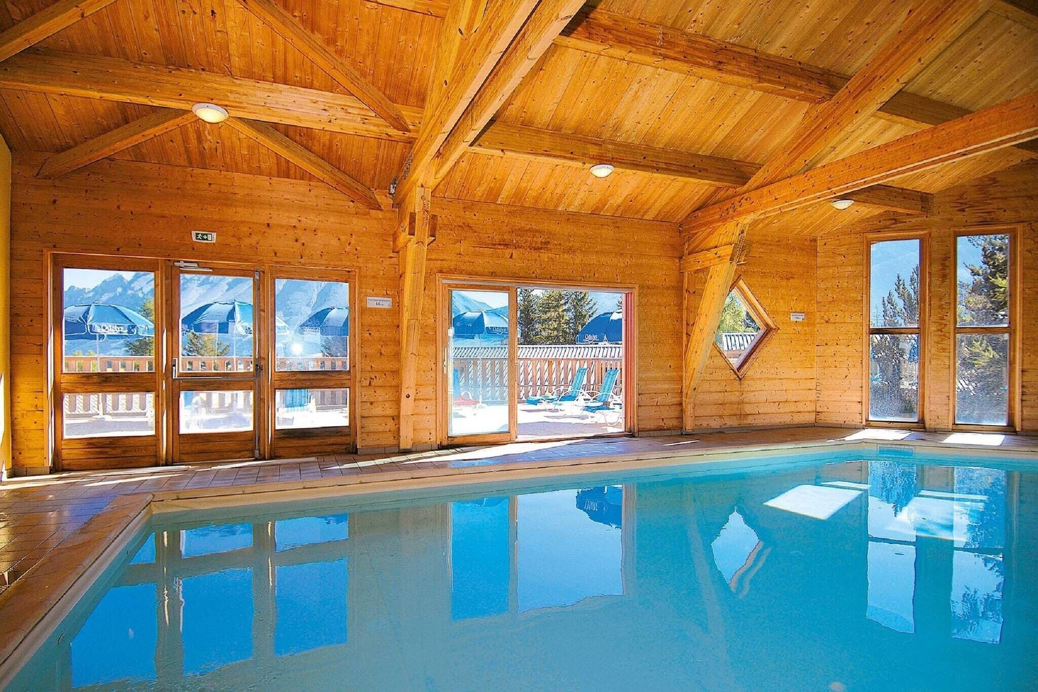 A wooden interior with a pool, large windows, and a view of the outdoors.