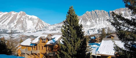 A snow-covered mountain landscape with wooden cabins and a clear blue sky.