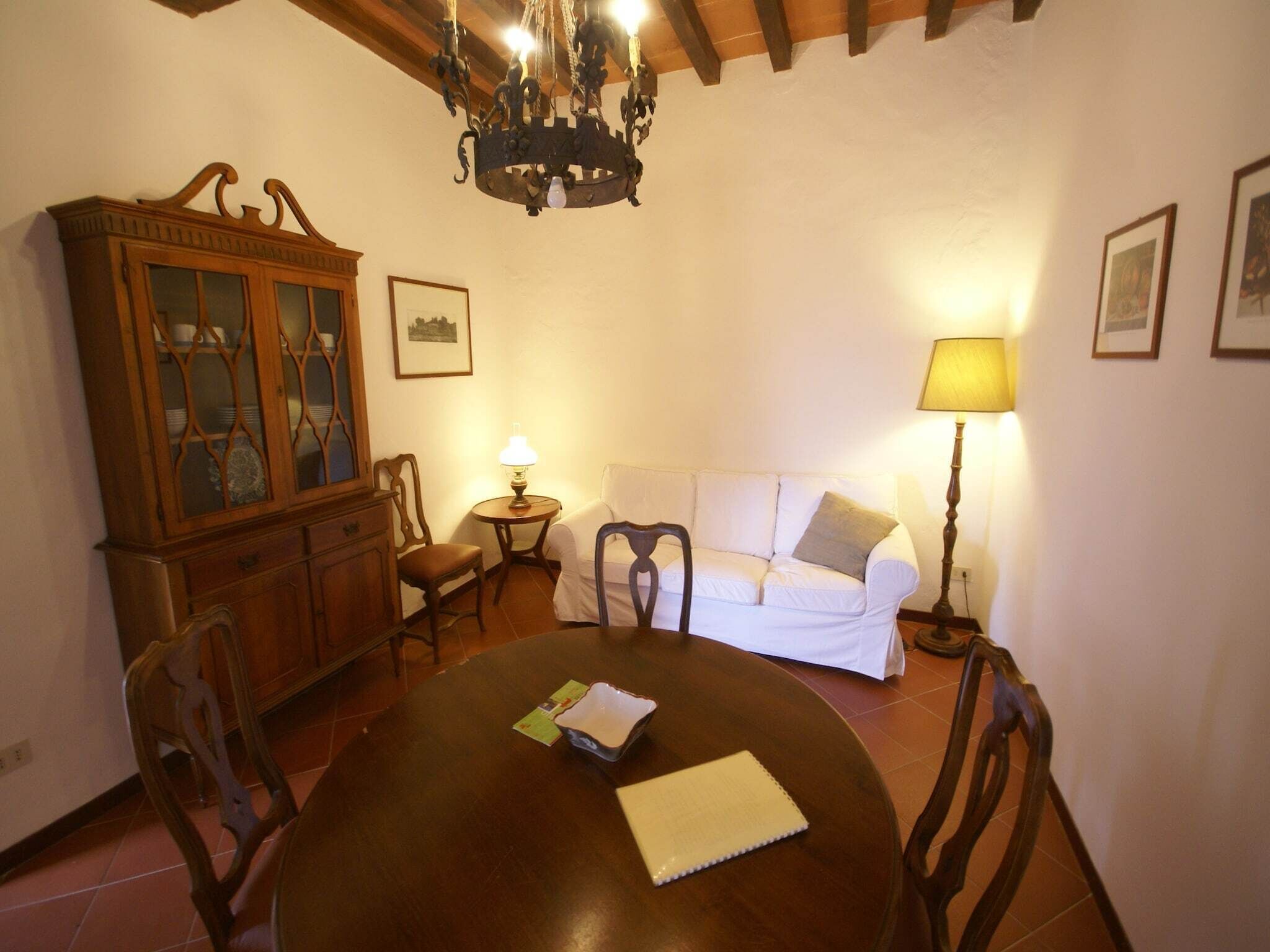 Un comedor con mesa de madera, sillas, sofá blanco y un aparador.