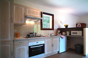 A kitchen with a stove, oven, microwave, and a window with bars.