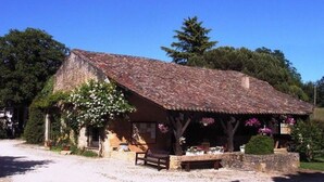 Un bâtiment rustique en pierre, doté d’un toit en pente, d’un banc à l’extérieur et d’un jardin fleuri.