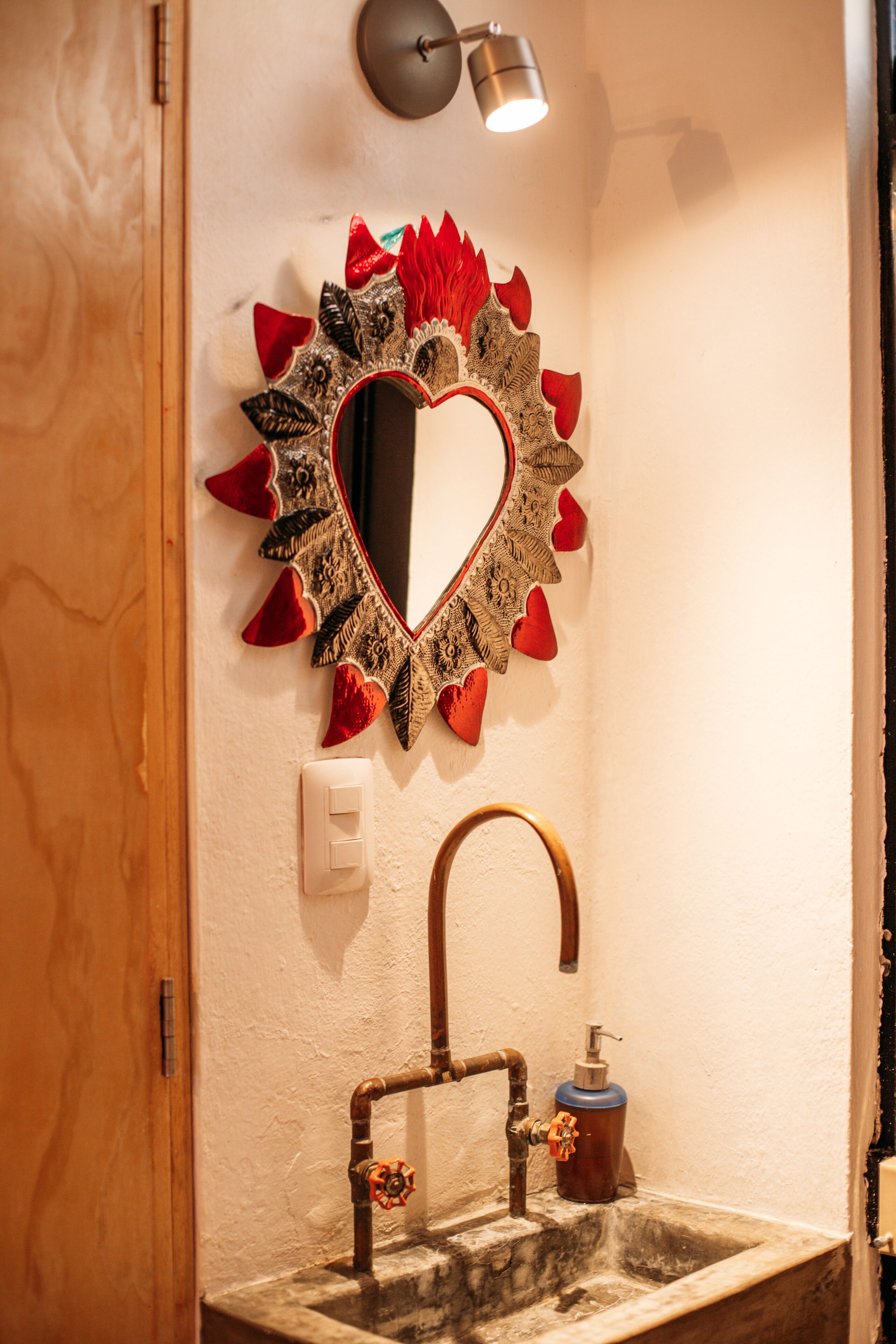 A bathroom with a decorative mirror, a sink with a faucet, and a soap dispenser.