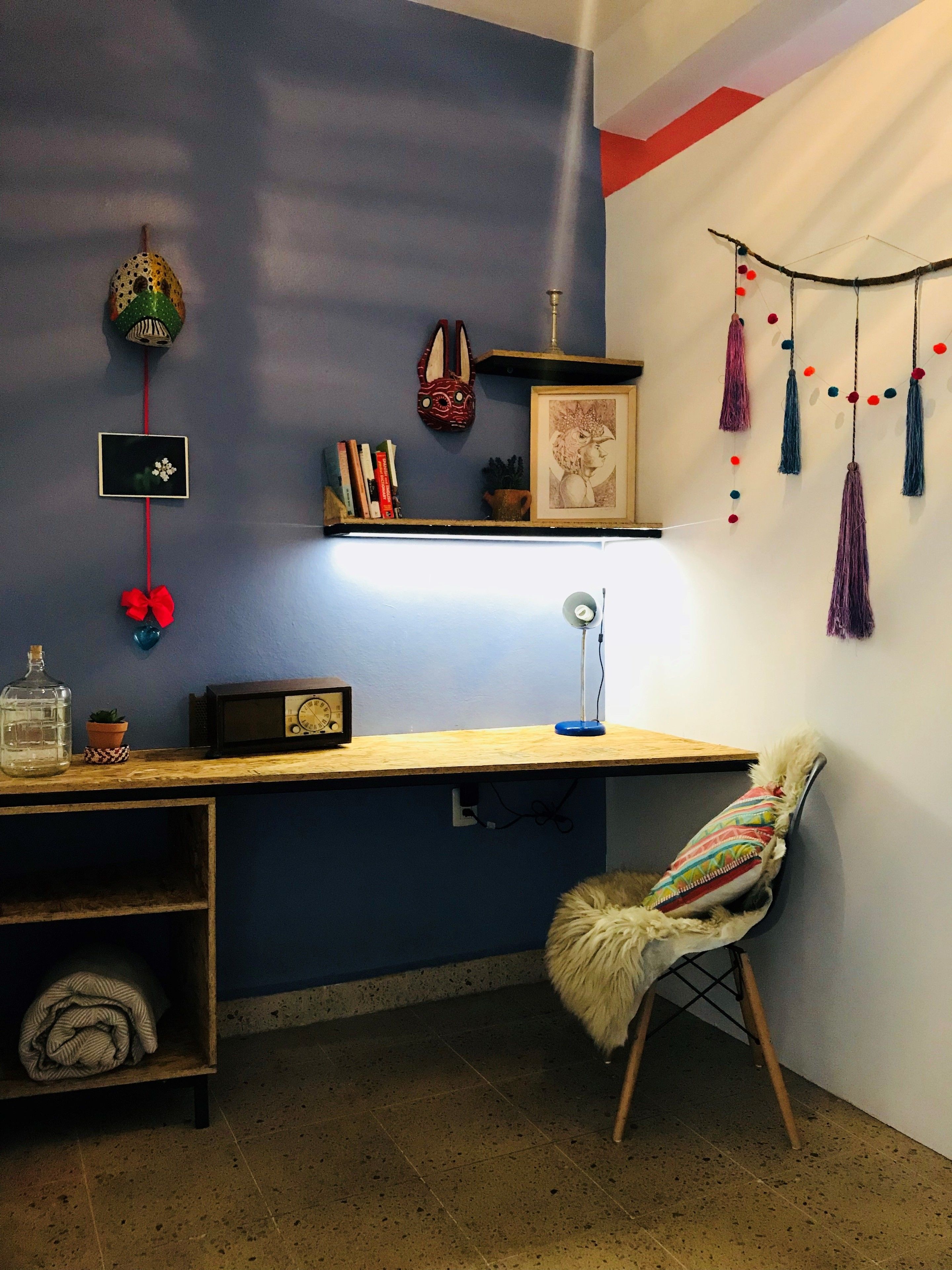 A cozy corner with a desk, chair, and shelves with books and decorative items.