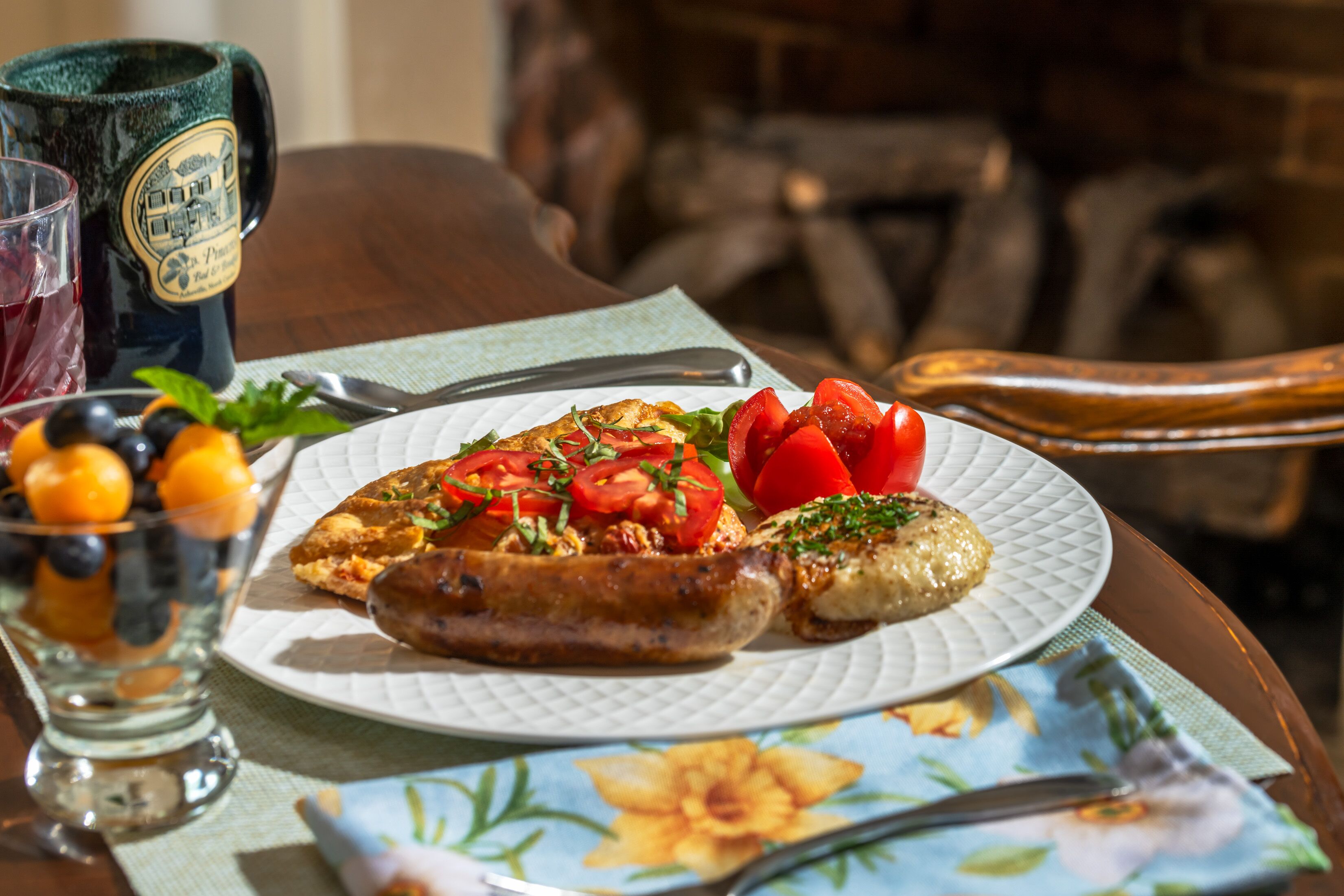 A plate with food, a glass with a beverage, and a mug on a table.