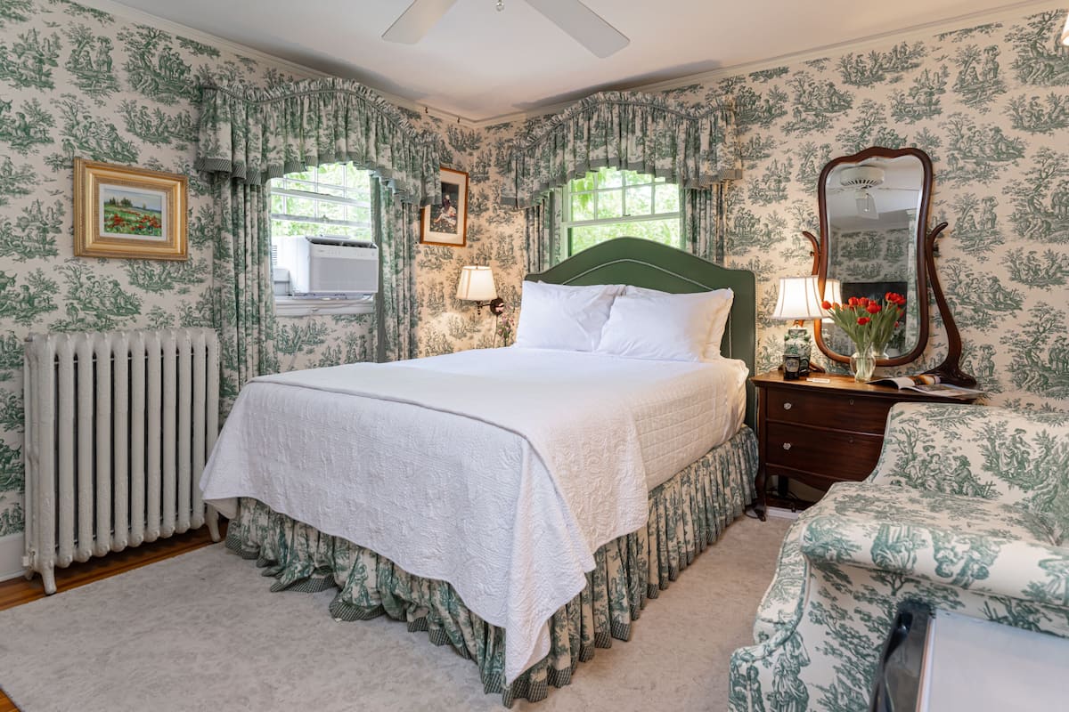 A bedroom with a large bed, a dresser, a mirror, and a radiator.