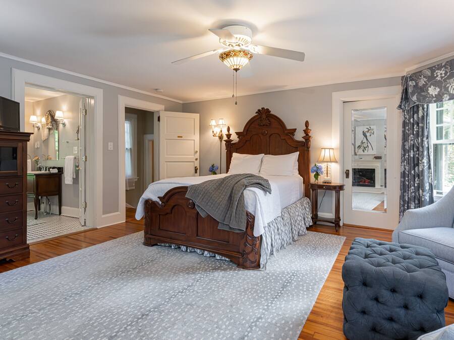 Une chambre à coucher avec un lit en bois, un ventilateur de plafond, une table de chevet, une lampe, une chaise et une commode.