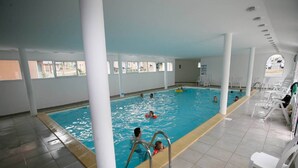 Una piscina interior amb aigua cristal·lina, envoltada de columnes blanques i un paviment de rajoles.