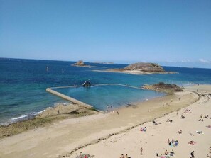A beach with clear blue water, a rocky outcrop, and a sandy shore. - Apartment in Brittany near Emerald Coast (Le Tronchet)