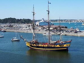 Ein großes Segelschiff liegt im Hafen vor einer Stadtkulisse.