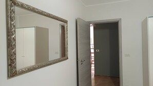 A hallway with a large ornate mirror, a door leading to another room, and a light switch on the wall. - Holiday Home in Giardini Naxos near Beach (Taormina Messina)