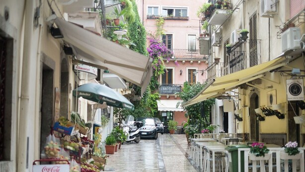 A narrow street with shops, outdoor seating, and parked cars. - Holiday Home in Giardini Naxos near Beach (Taormina Messina)