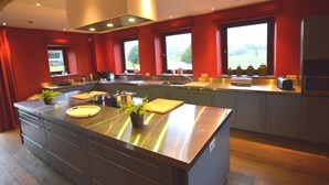 A modern kitchen with a large island, stainless steel appliances, and red accents. - Holiday Home in Falaën with Garden BBQ (Stave)