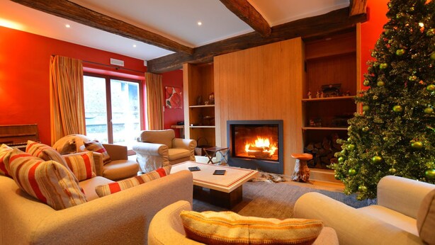 A cozy living room with a fireplace, a Christmas tree, and a sofa with striped cushions. - Holiday Home in Falaën with Garden BBQ (Stave)