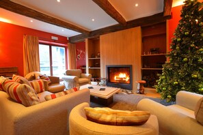 Een gezellige woonkamer met een open haard, een kerstboom en een bank met gestreepte kussens.