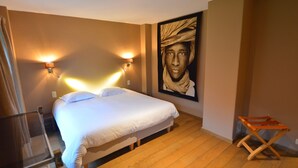 A bedroom with a bed, two wall-mounted lights, a wooden floor, and a large framed picture on the wall. - Holiday Home in Falaën with Garden BBQ (Stave)