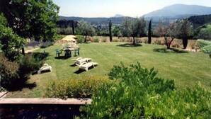 A well-maintained lawn with outdoor furniture, surrounded by trees and a mountainous backdrop. - Holiday Home near Mont Ventoux Pool (Vaison-La-Romaine)